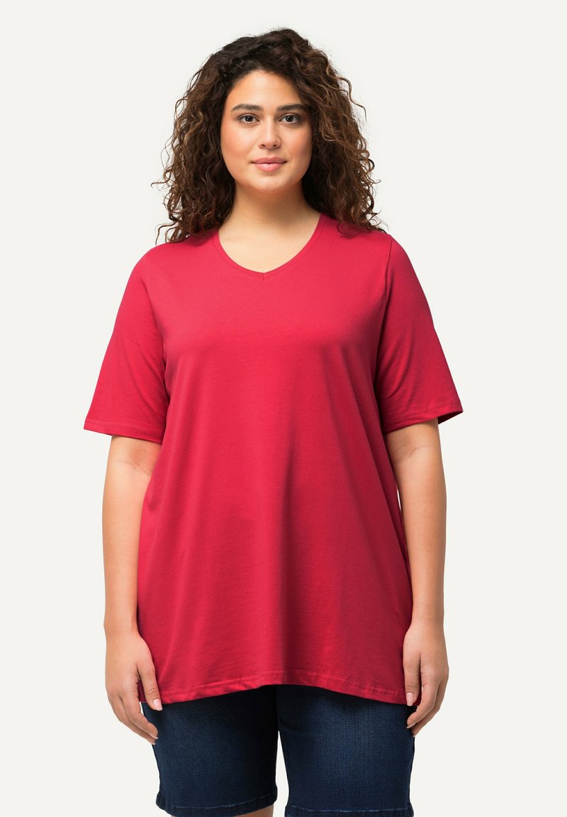 Maglietta rossa a maniche corte con scollo a V, vestibilità comoda, tessuto morbido e texture liscia. Abbinata a pantaloni corti di jeans scuri per un look informale.