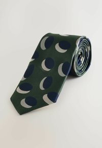 Groene stropdas met een gestructureerde weef, voorzien van marineblauwe en grijze maanvormige patronen. Opgerold met een spitse punt, wat een modern ontwerp toont.
