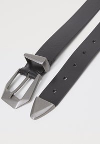 Ceinture en cuir noir avec une boucle carrée en métal argenté mat et une extrémité pointue. Présente plusieurs trous pour un ajustement et une finition texturée.