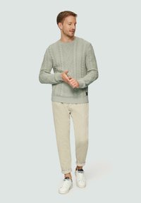 Hellgrüner, gestrickter Pullover mit strukturierten Rautenmuster, kombiniert mit beigen Cordhosen und weißen Sneakern. Lässige Passform.