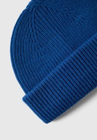 Sinine kudumine beanie, millel on soonik tekstuur ja volditav äär. Omab sujuvat viimistlust kerge sära ja on valmistatud pehmest villasegust materjalist.