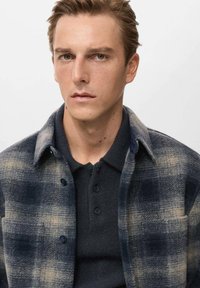 Košeľa s gombíkmi, flanelová, v námorníckej a béžovej kocke, vyrobená z textúrovaného materiálu. Obsahuje golier, predné gombíky a náprsné vrecko.