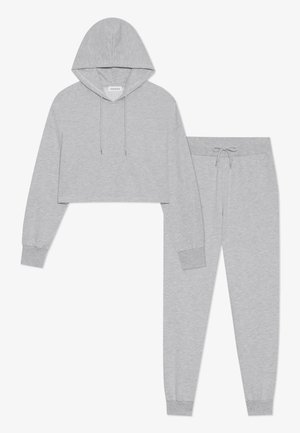 Grijze cropped hoodie met trekkoord en lange mouwen, gecombineerd met bijpassende grijze sweatpants met een elastische tailleband en trekkoord.