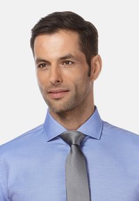 Lichtblauw overhem Shirt met een kraagnek, aangevuld met een gestructureerde grijze stropdas. De stof lijkt glad met een subtiele glans.