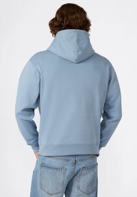 Felpa con cappuccio azzurro chiaro in tessuto morbido, dal taglio comodo e con tasca a marsupio, abbinata a jeans azzurro chiaro.