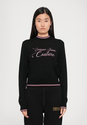 Black knit sweater with a ribbed collar and cuffs, featuring pink embroidered "Versace Jeans Couture" text on the front and a fitted design.
