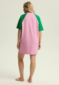 Oversized sukienka T-shirt w różowym i zielonym kolorze. Posiada krótkie rękawy, okrągły dekolt i luźny krój z miękkiego materiału bawełnianego.