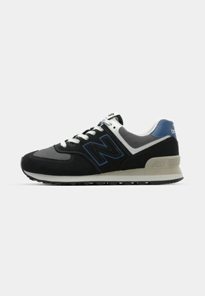 Baskets noires et grises avec des accents bleus, fabriquées en daim et en maille. Dotées d'une semelle rembourrée et d'un logo bien visible sur le côté.