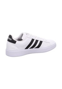 Weißer Adidas-Sneaker mit schwarzen Streifen und Fersenlasche, niedrigem Schnitt, Schnürverschluss und gepolsterter Sohle.