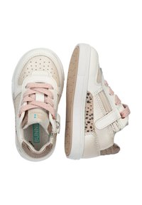 Baskets en cuir couleur crème avec des lacets et des accents roses, présentant un design perforé et une sangle en Velcro. Semelle en caoutchouc à profil bas.