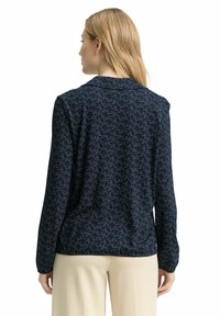 Navybluse mit einem durchgehenden abstrakten Muster in Hellblau, langen Ärmeln und Kragen. Glatter Stoff mit lockerem Schnitt.