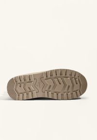 Beige gummisul med ett zigzag-mönster, med framträdande spår och en texturerad yta för grepp, märkt "OYSIHO 37."