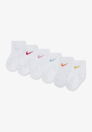Six chaussettes blanches pour bébé avec des logos Nike Swoosh de différentes couleurs en argent, rouge, rose, bleu, orange et jaune, disposées en rangée.