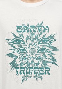 Λευκό πουκάμισο με πράσινο γραφικό που δείχνει πολλαπλά μάτια να περιβάλλουν μια γη και κείμενο που γράφει "Earth Tripper Volcom Stone".