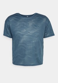 Niebieska koszulka z krótkim rękawem z wzorem fali, wykonana z miękkiego materiału. Posiada okrągły dekolt i małe logo z przodu.