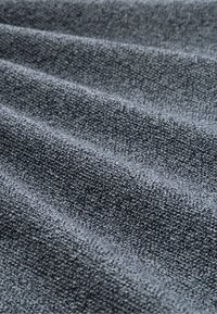 Donkergrijs, gestructureerd stof met zichtbare weefpatroon en subtiele schaduwvariaties, gedrapeerd om diepte en contour te tonen.