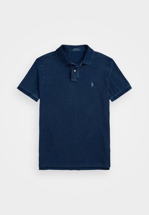 Tumši zilas krāsas polo krekls, izgatavots no kokvilnas, ar klasisku apkakli, divu pogu aizdari, īsām piedurknēm un izšuvumu uz krūtīm.