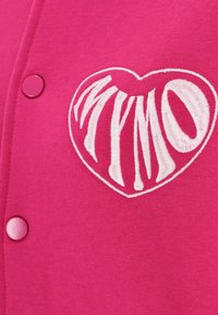 Fuchsia cardigan met witte geborduurde tekst "MYMO" in hartvorm. Glad materiaal met roze drukknoopjes.