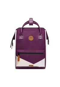 Zaino in tela viola con un accento triangolare bianco, tasca frontale con cerniera, manico in pelle e patch con logo. Presenta spallacci testurizzati e cerniera.