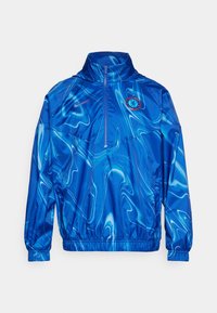 Niebieska sportowa kurtka z długim rękawem z wirującymi wzorami, z pół zamkiem błyskawicznym, elastycznymi mankietami oraz logo Chelsea FC i Nike na klatce piersiowej.