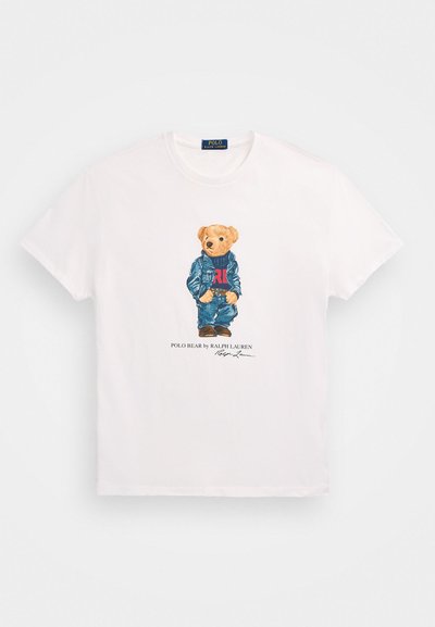 Λευκό βαμβακερό μπλουζάκι με εκτυπωμένη αρκούδα που φοράει μπλε σακάκι και κόκκινο πουλόβερ, με το κείμενο "Polo Bear by Ralph Lauren" κάτω από την εικονογράφηση.