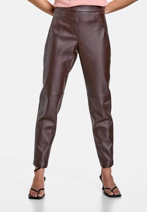 Pantalons en cuir marron au design ajusté, avec une taille haute, des coutures discrètes et des jambes fuselées. Texture lisse et finition élégante.