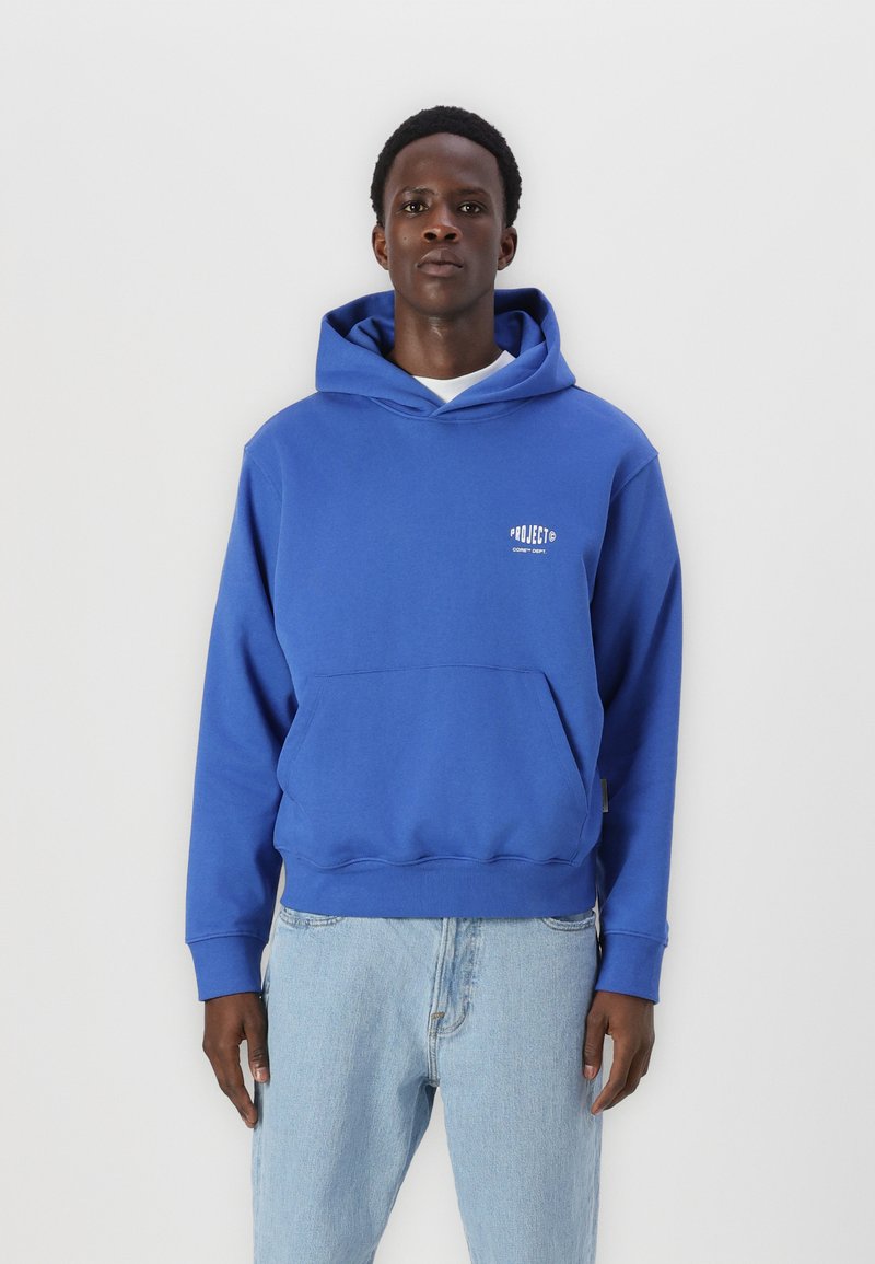 Blaues Baumwoll-Hoodie mit einer Vordertasche und Logodetails. Kombiniert mit hellblauen Jeans. Schlichtes Design und lockere Passform.