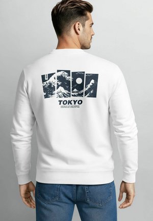 White sweatshirt featuring a graphic design of mountains and a sun, with "TOKYO" text below and a soft texture.