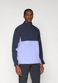 Pulover cu fermoar de un sfert în nuanțe de bleumarin și lavandă deschisă; are mâneci lungi, guler înalt și material texturat pentru izolație.