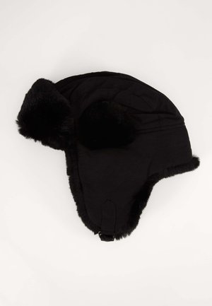 Juodas kailiniuotų pamušalu trapperio skrybėlė su sijono audiniu, turinti ausų užklotus ir smakro dirželį, leidžiantį reguliuoti dydį. Minkšta tekstūra visame paviršiuje.