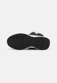 Sole in gomma nera con un motivo testurizzato caratterizzato da forme esagonali e righe per una migliore aderenza; parte superiore tipo calza bianca con bordo soffice.