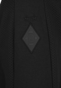 Tessuto nero con pannelli laterali dalla texture che mostrano un logo a forma di diamante cucito con una lettera B e due stelle ricamate sopra.