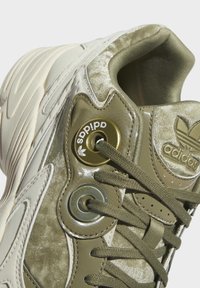 Olivgrön sneaker med texturerad ovandel, glansiga detaljer och runda öglor. Har ton-i-ton snören och en vadderad krage.