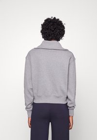 Maglione grigio con un ampio colletto, maniche lunghe e orlo corto. Realizzato in materiale morbido, presenta polsini e orlo a coste.