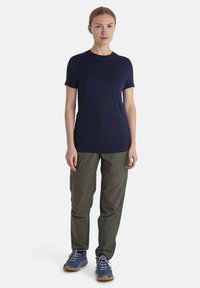 Námořnické tričko s krátkým rukávem v kombinaci s olivově zelenými kalhotami a modrými sportovními botami. Jednoduchý design, lehký materiál, uvoln�ěný střih.
