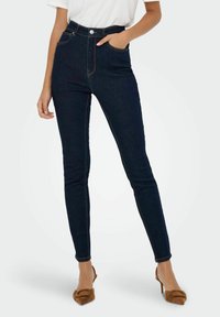 Hoge taille donkere denim jeans met een slanke pasvorm, twee voorzakken, gele stiksels en een knopenversiering op de taille.