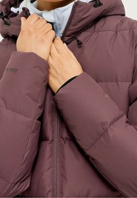 Dunkelmaulbeerenfarbener Puffer-Jacke mit Reißverschluss, verstellbarer Kapuze mit Zugbändern und gerippten Bündchen. Glattes, isoliertes Material.