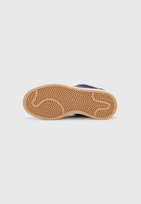 Semelle de chaussure avec une surface en caoutchouc texturé de couleur brune, présentant un motif de semelle en zigzag pour l'adhérence et la stabilité. Le design est minimaliste.