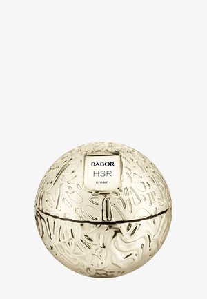 Rund, texturerad krämburk i guld med en slät yta. Har en vit etikett med texten "BABOR HSR cream" på toppen.