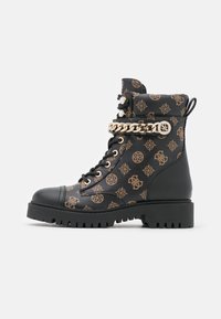 Bottes de combat noires avec un motif marron, embout renforcé, chaîne décorative dorée et semelle robuste pour une meilleure adhérence.