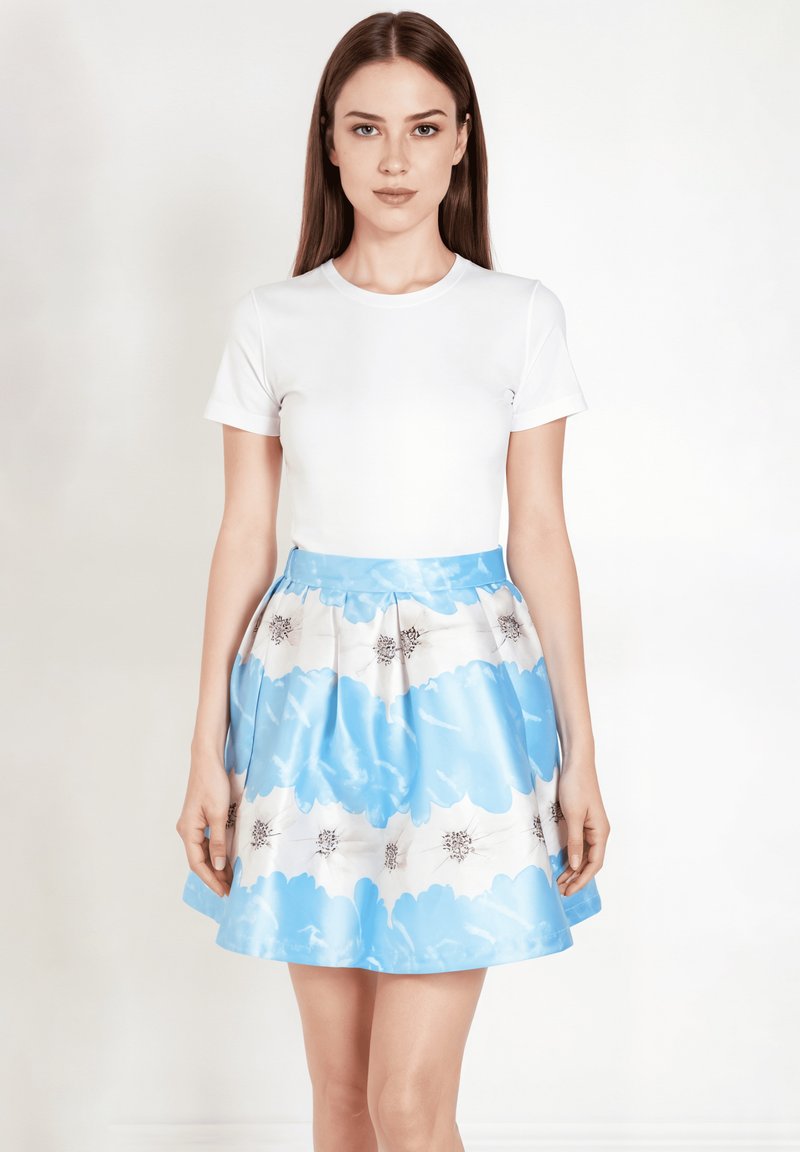 Camiseta blanca de manga corta combinada con una falda plisada que presenta un patrón de nubes azules y acentos florales sobre un fondo blanco.