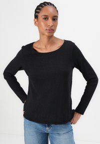 Black long-sleeve top with a round neckline. Made of lightweight fabric, featuring a simple design and a relaxed fit. Worn with blue jeans.