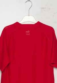Maglietta rossa a maniche corte realizzata in tessuto leggero, con scollo tondo e logo Puma stampato in bianco sulla parte posteriore vicino al collo.