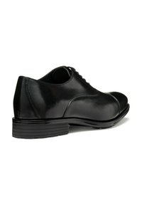 Zapato de vestir negro de cuero con textura suave, punta redondeada, diseño con cordones y una suela de goma texturizada y baja. Estilo clásico y minimalista.