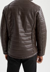 Giacca in pelle marrone con design trapuntato, cuciture orizzontali e silhouette aderente. Texture liscia con una finitura leggermente lucida.