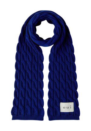 Blauer gestrickter Schal mit dickem Zopfmuster und einem weißen rechteckigen Etikett mit der Aufschrift "oui" an einem Ende.