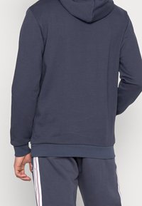Sudadera azul marino para hombres, hecha de tejido suave, con un bolsillo canguro y capucha con cordones, y puños y dobladillo acanalados.