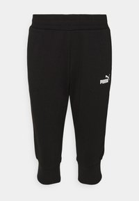 Svarta knälånga sweatpants gjorda av mjukt material. Har en elastisk midja och en vit Puma-logotyp på vänstra låret.