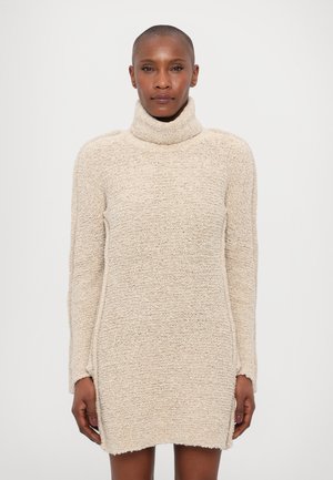 Beež turtleneck kleit, mis on valmistatud tekstureeritud kudumikoest, pikad varrukad ja keskmise reie pikkusega hemline, millel on toored servad.