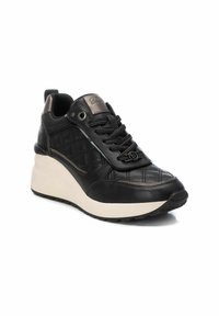 Zapatillas de cuero negro con textura acolchada, diseño de cordones y suela en color beige con cuña. Presentan acentos metálicos y un logotipo discreto en la lengua.